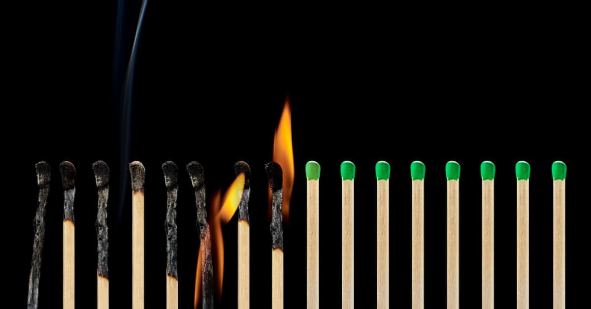 A half burnt row of burning matchsticks about to light the unburnt half row of matchsticks 