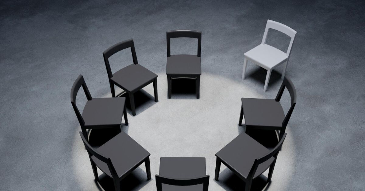 A white chair away from a circle of black chairs facing each other