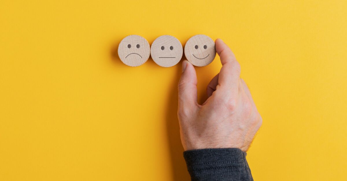 Person placing a wooden smiley chip next to a series of chips