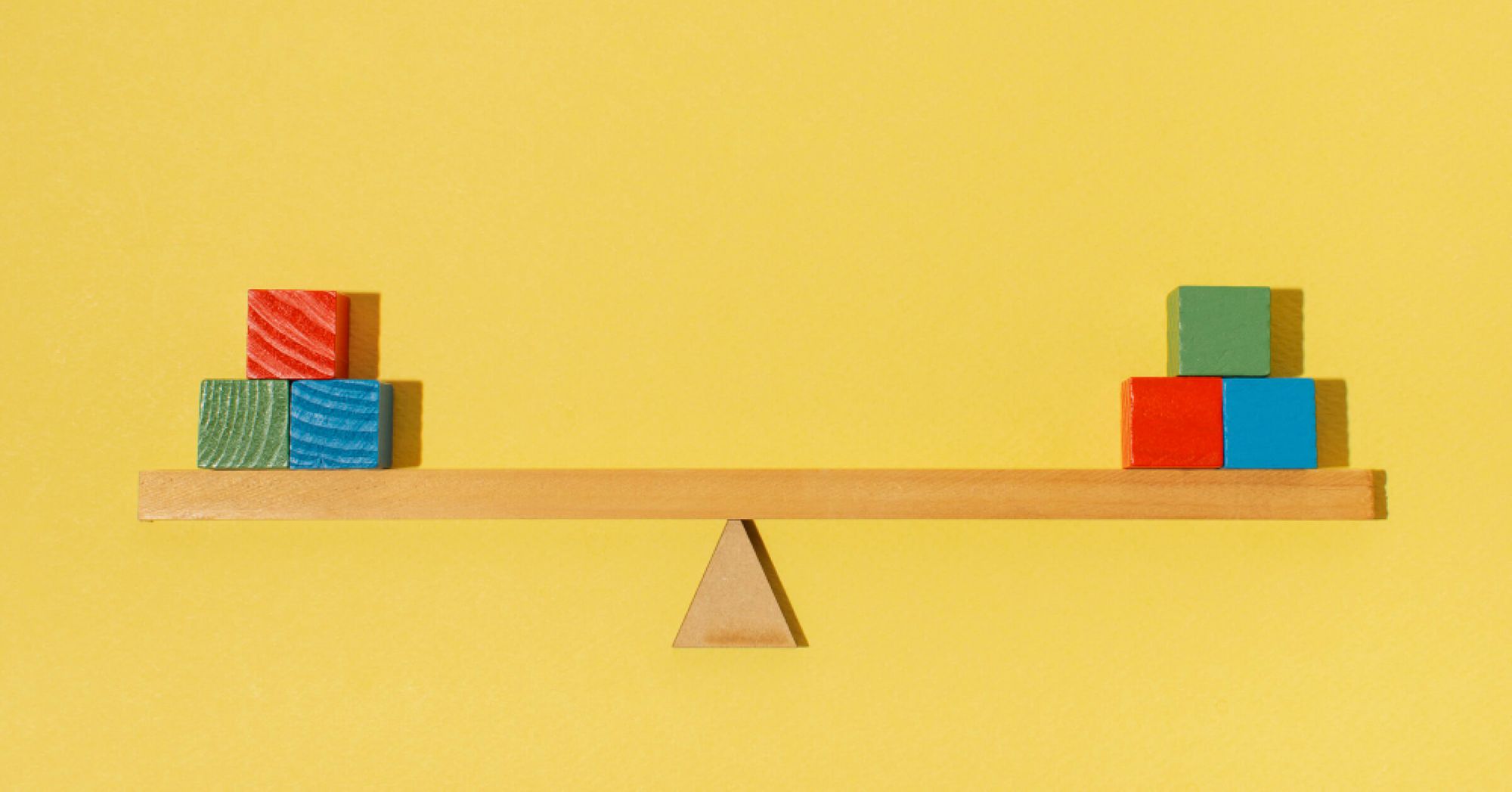 Coloured blocks balanced on both ends of a plank