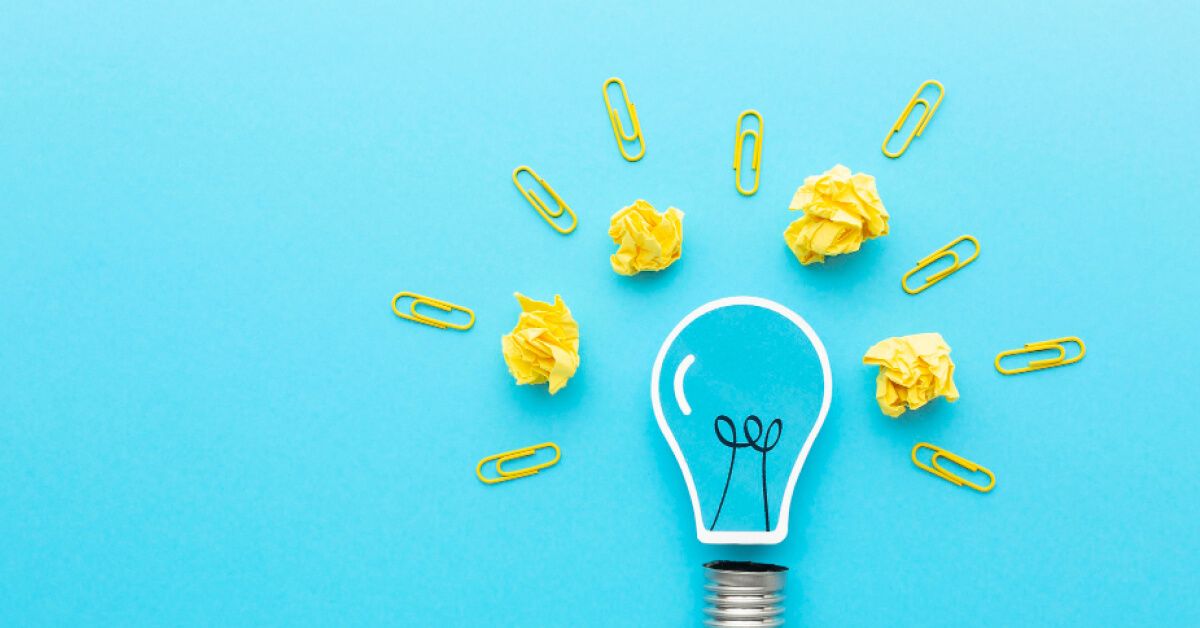 Yellow pins and crushed paper balls around a vector lightbulb