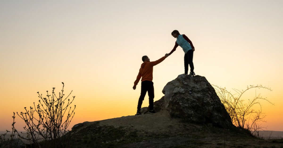 Person helping someone climb a short hill