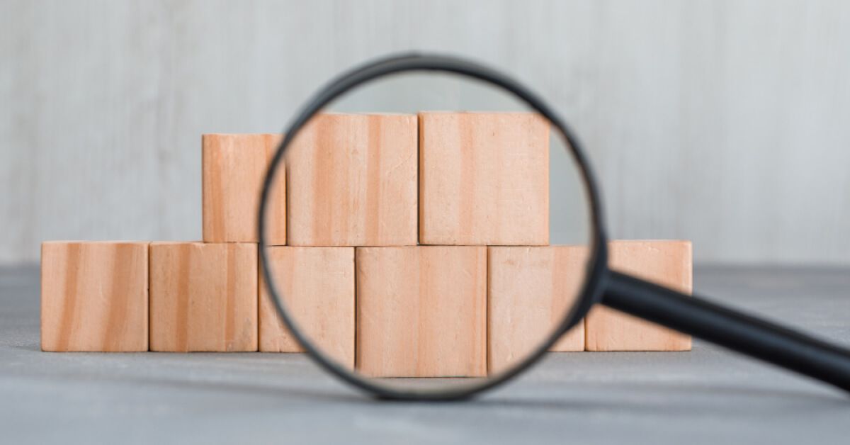 Magnifier glass pointing over a stack of wooden blocks