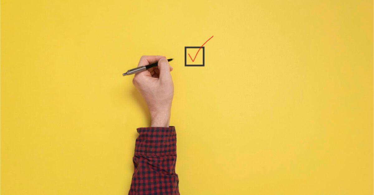 Person checking a box against a yellow backdrop
