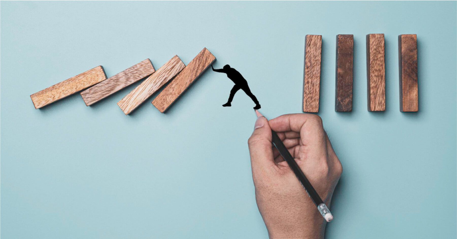 Person drawing a figurine stopping wooden blocks from falling over