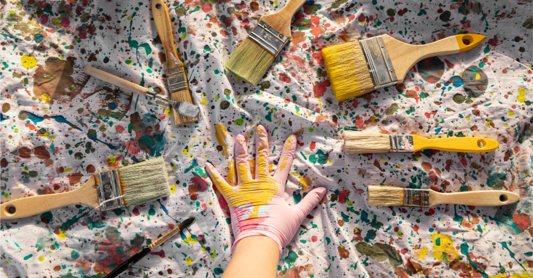 Top view of paintbrushes with paint and artist hand