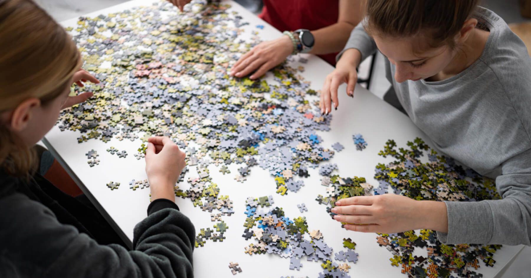 Girls putting puzzle pieces together on table