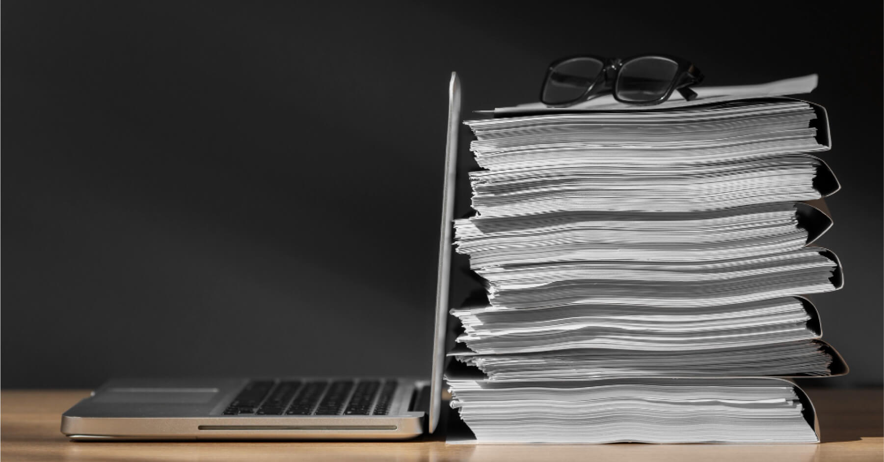 A stack of files next to an open laptop