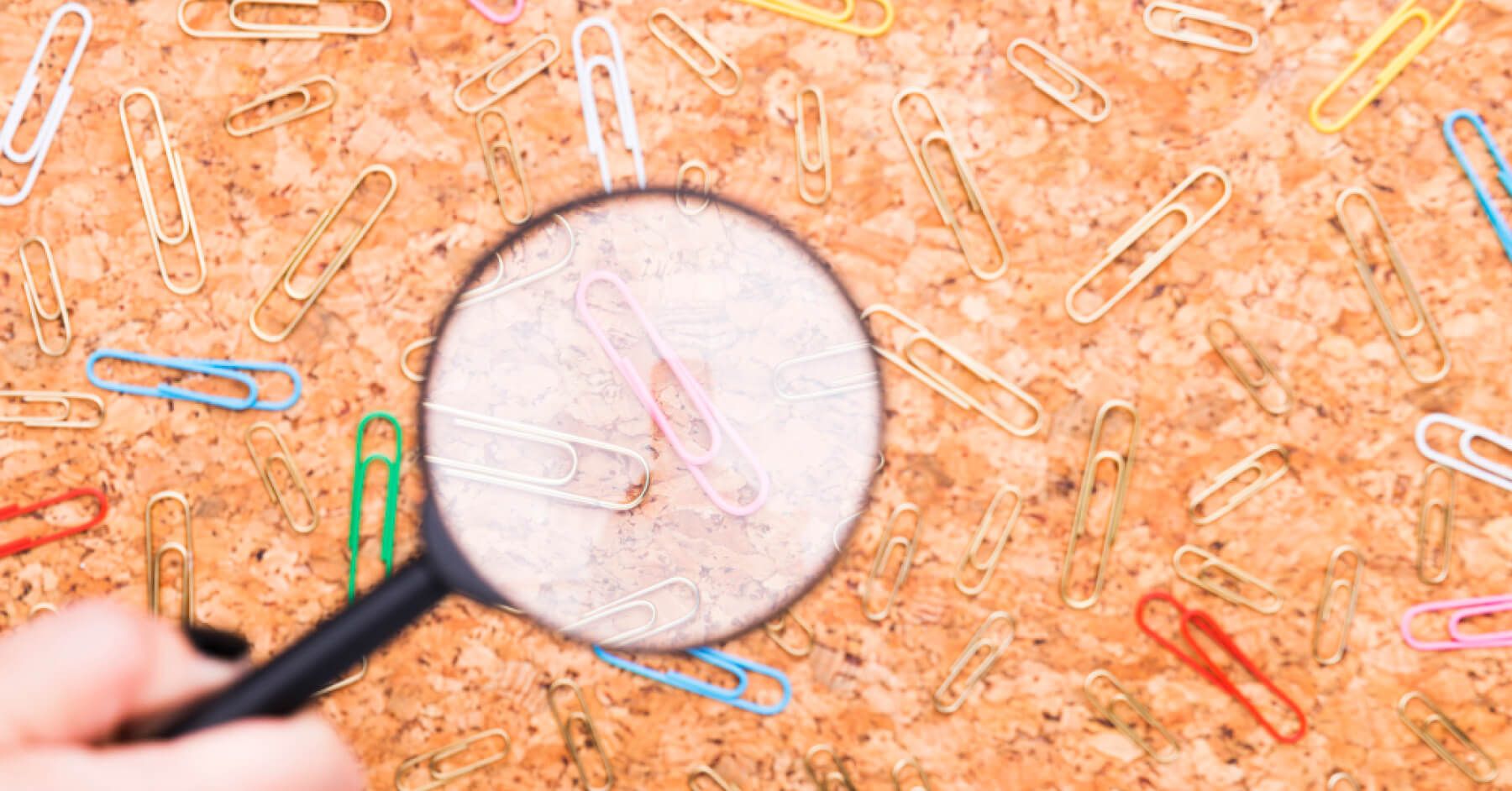 Magnifier glass over multicoloured pins