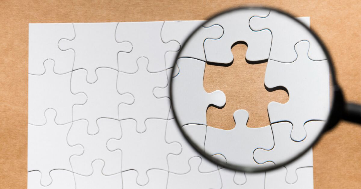 Magnifier glass over a missing puzzle piece