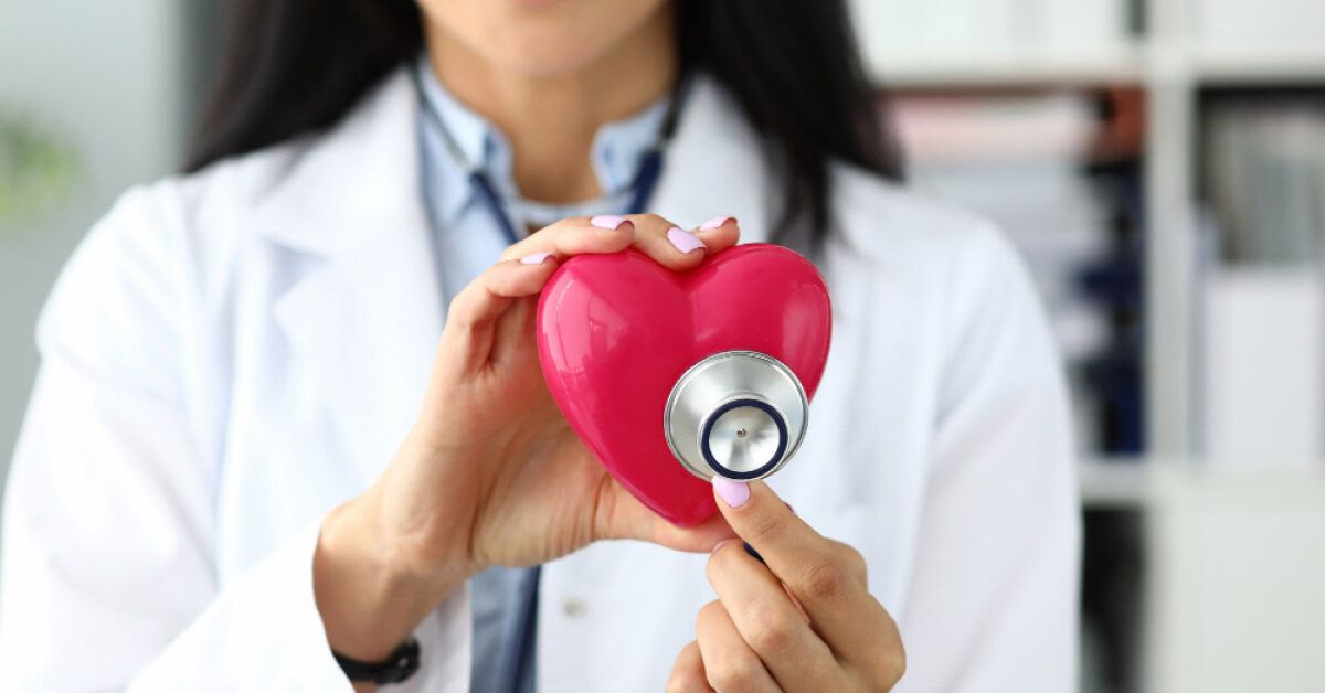 Doctor listening to a plastic heart's beat