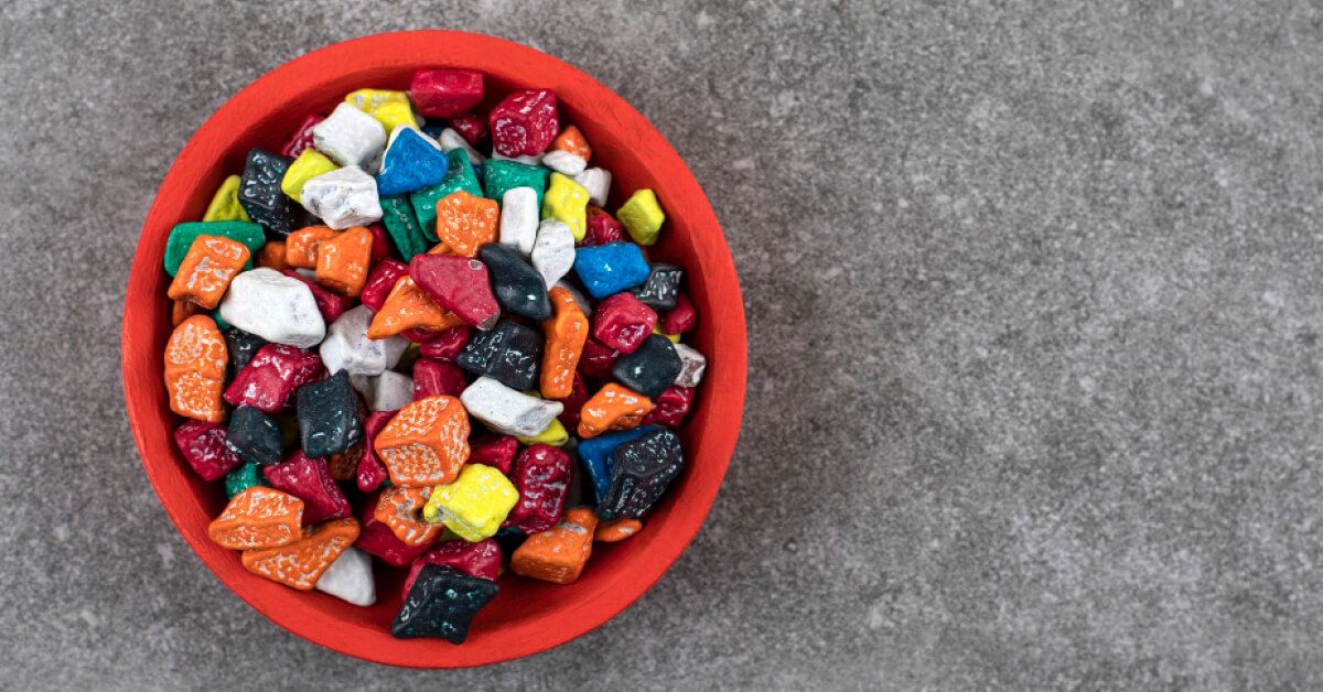 Red bowl of colorful stone candies on stone