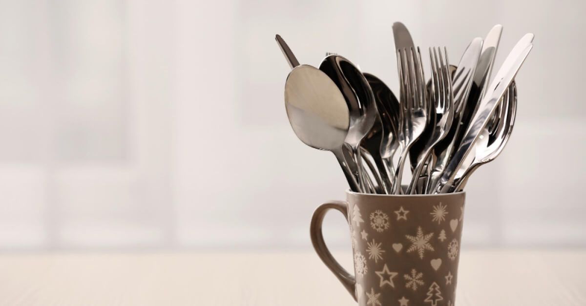 Metal kitchen utensils in ceramic cup on table