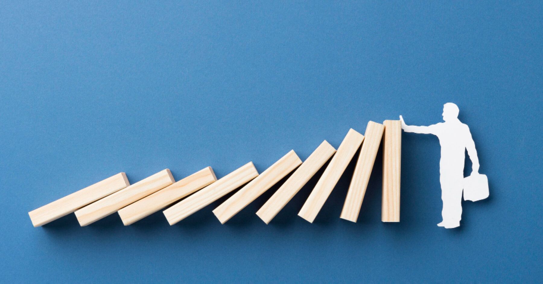 Cutout of a person stopping a series of wooden blocks from falling over