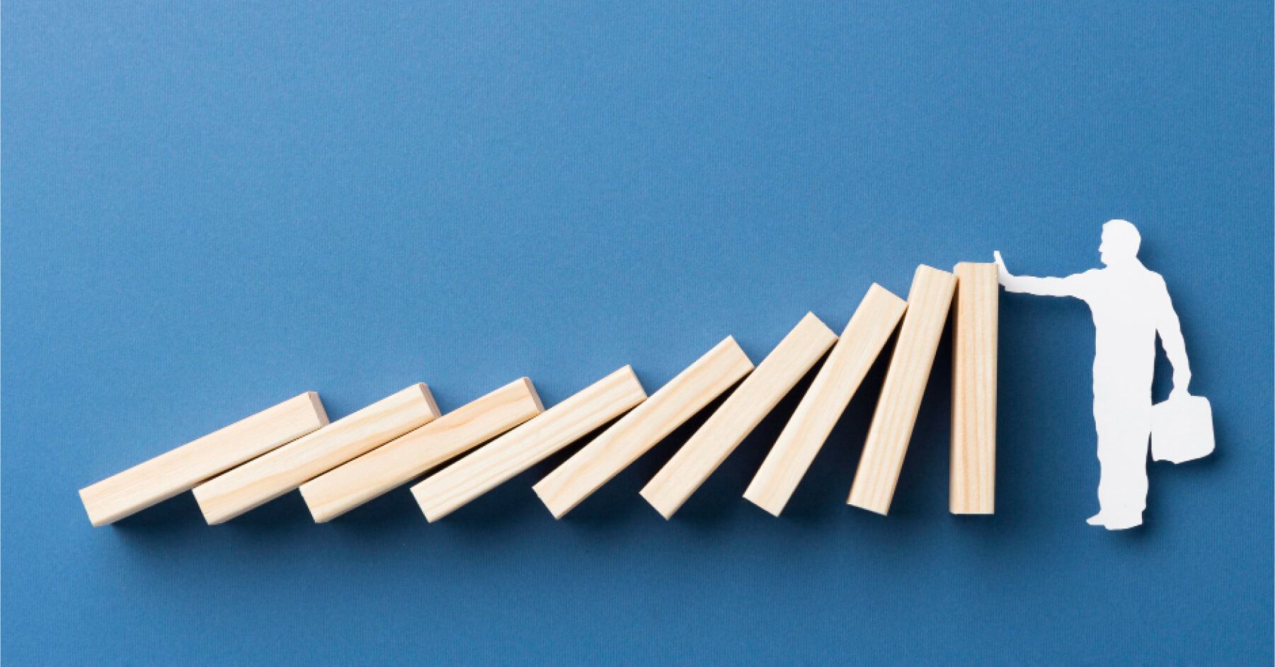 Cutout of a person stopping a series of wooden blocks from falling over