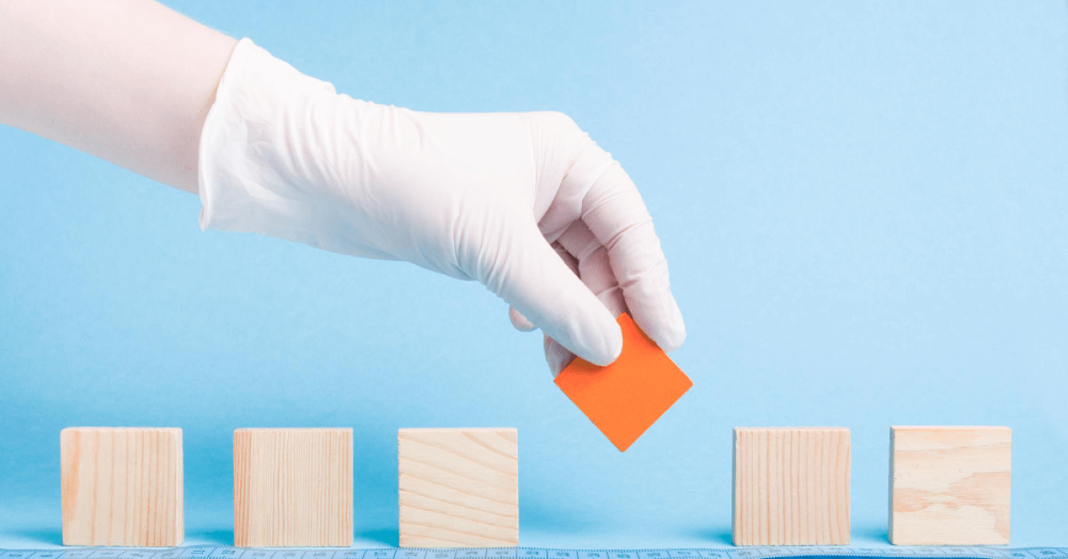 Person placing an orange shape into a series of wooden blocks
