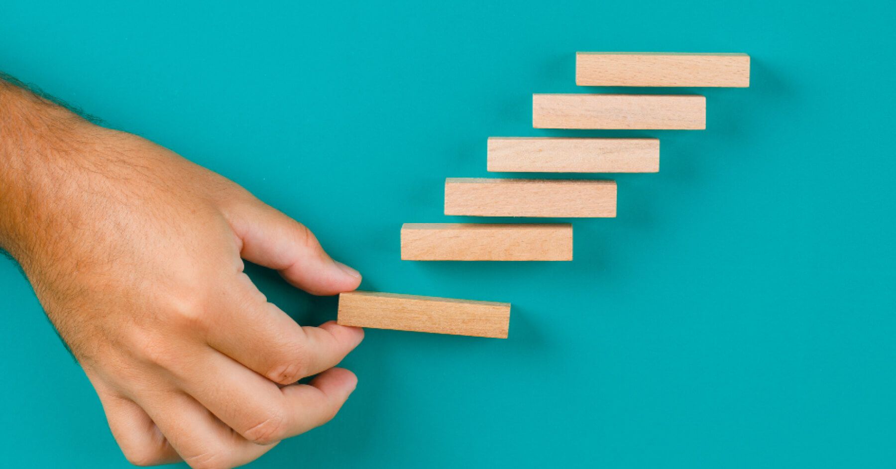 Person arranging wooden blocks in a stepped manner