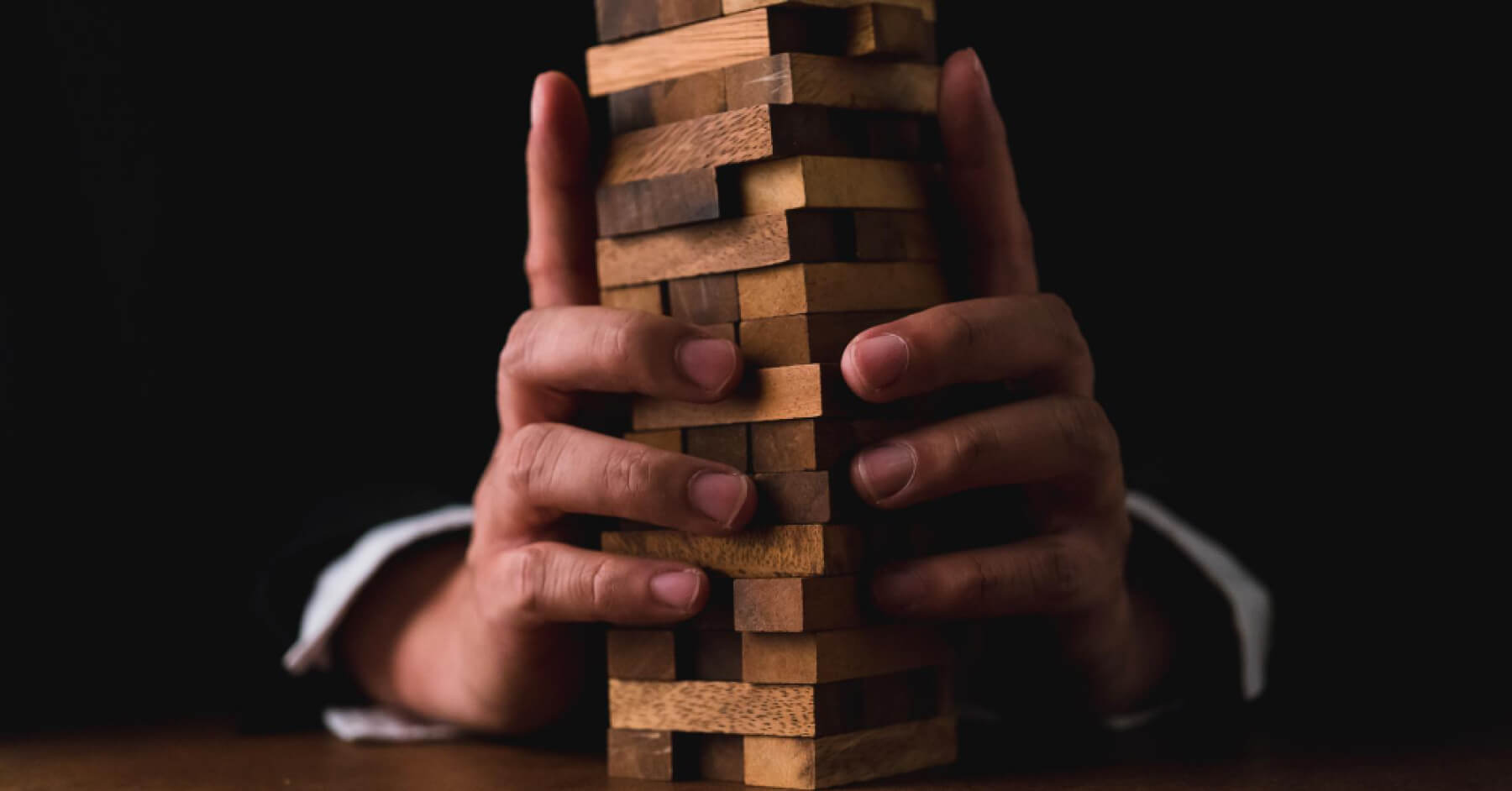Person arranging an interlinked wooden block tower