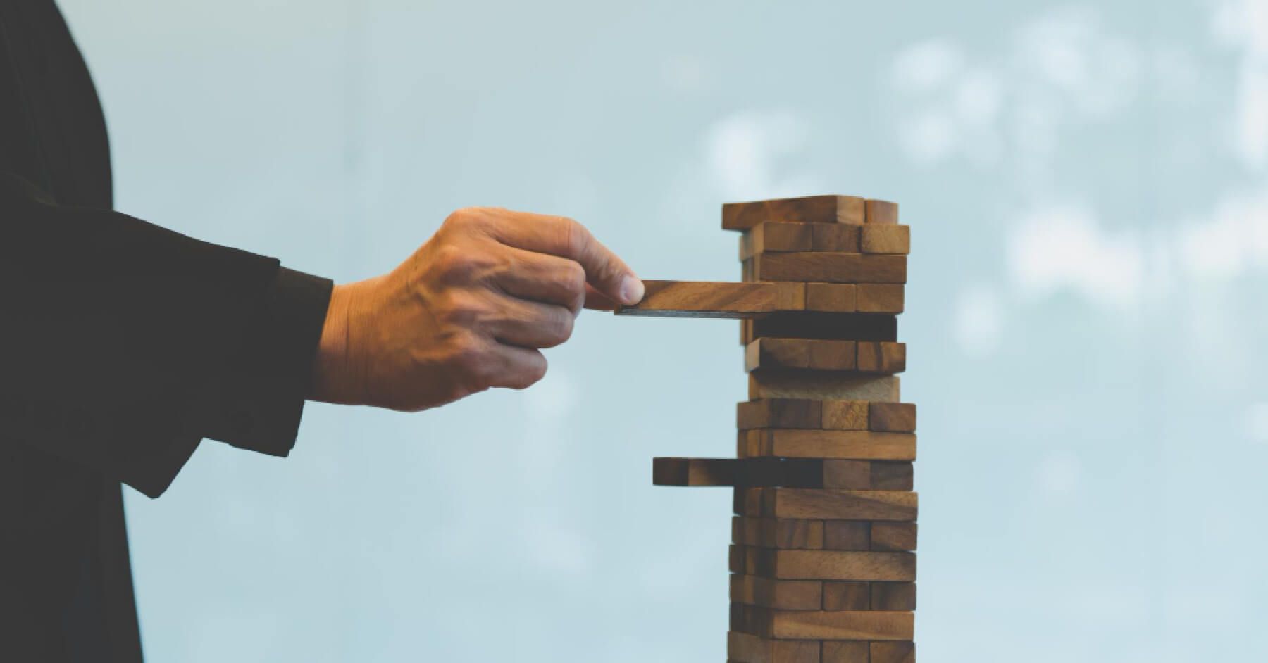 Person inserting a wooden block into a grid of wooden blocks