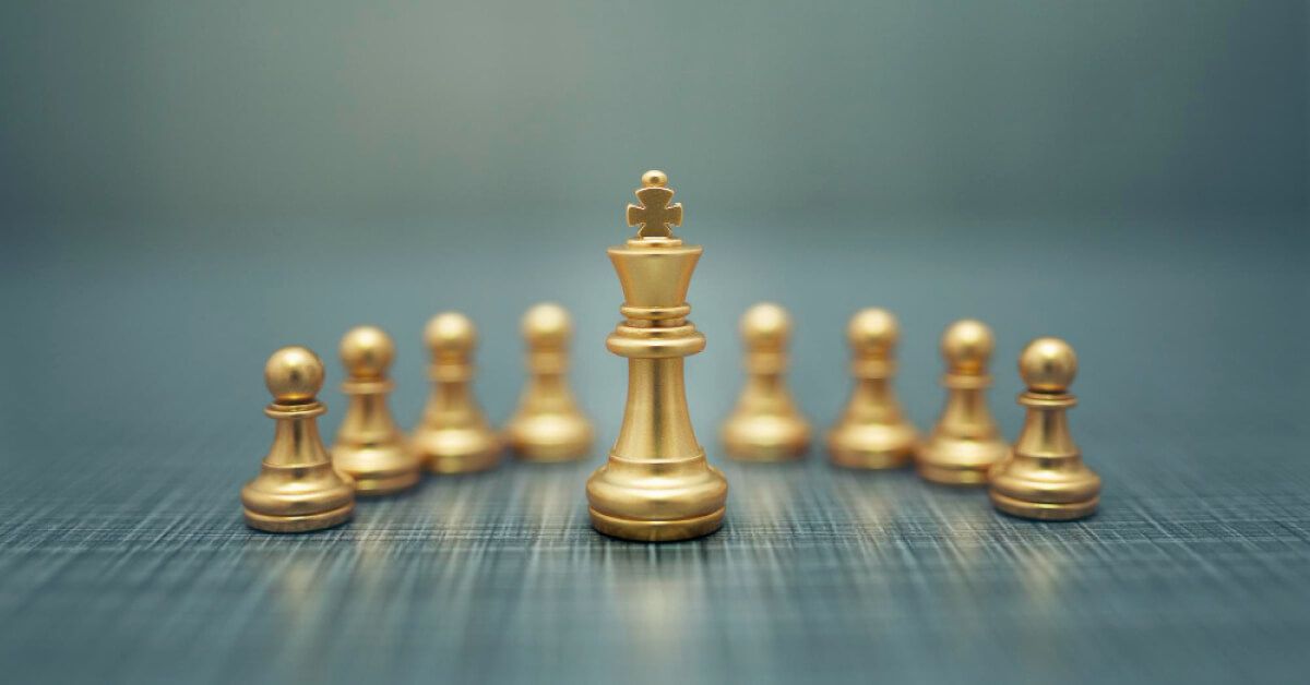 Golden chess pawns around a king piece