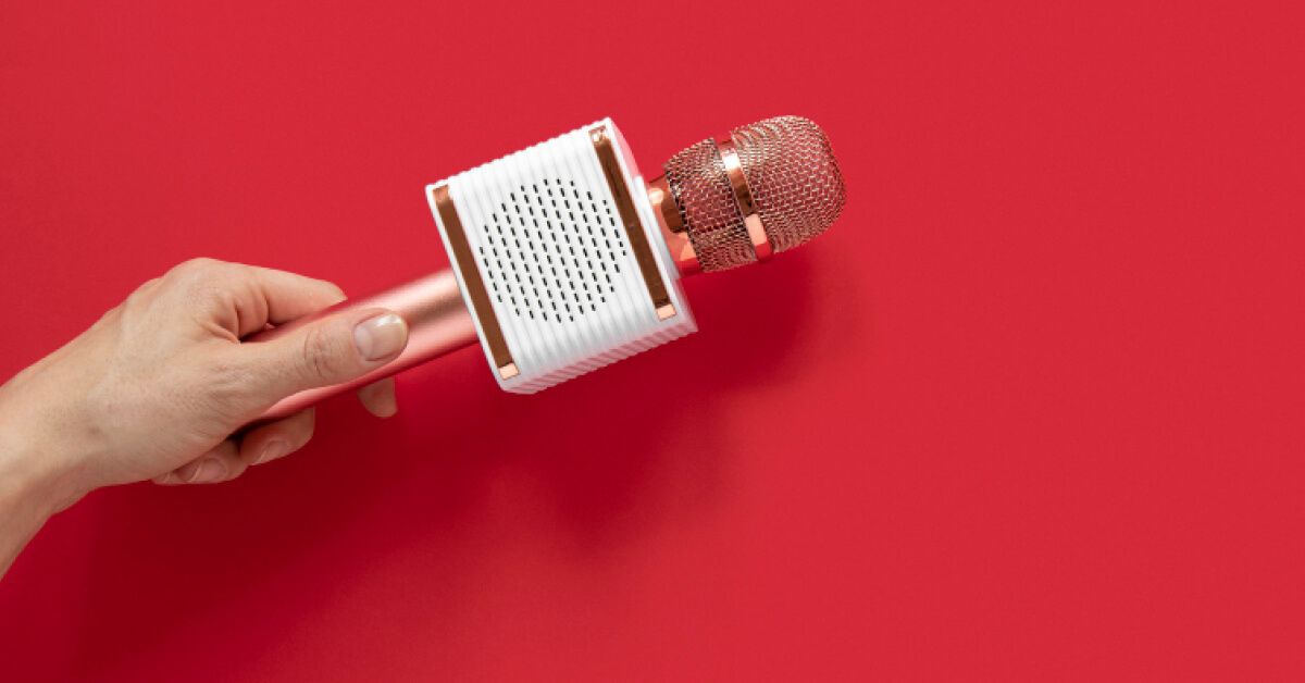 Person holding a microphone against a red backdrop