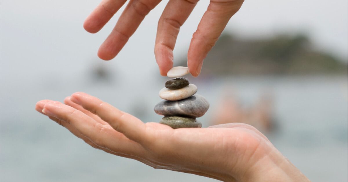 Person stacking pebbles on a palm
