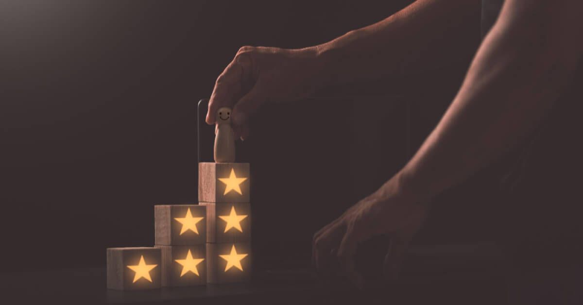 Hand placing a wooden pawn on other wooden blocks that has stars