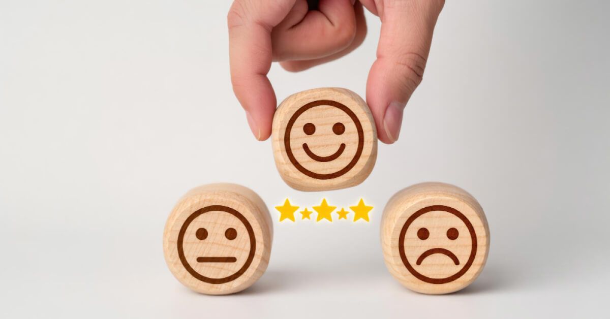 Three wooden blocks of happy, sad and indifferent emojis along with five stars