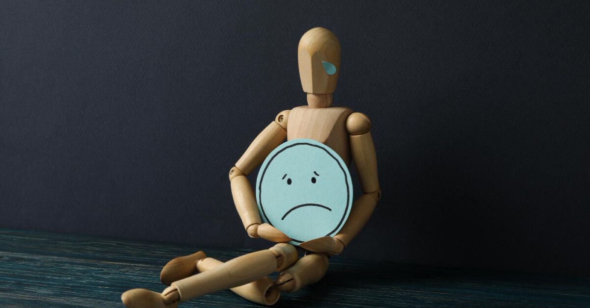 Wooden toy holding a sad cutout face