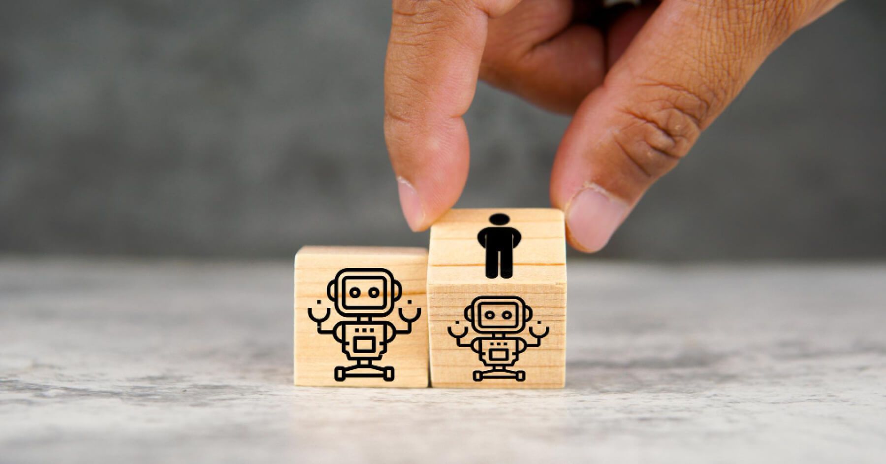 Two wooden blocks of robots being turned by a hand