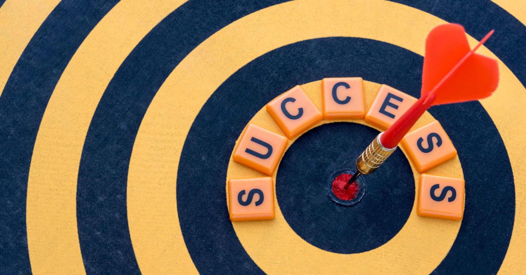 Dart hitting the eye of a board along the words success written around it