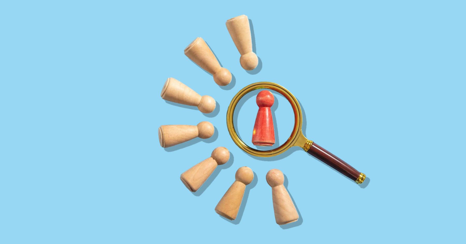 Magnifying glass surrounding a red wooden pawn amongst other brown wooden pawns