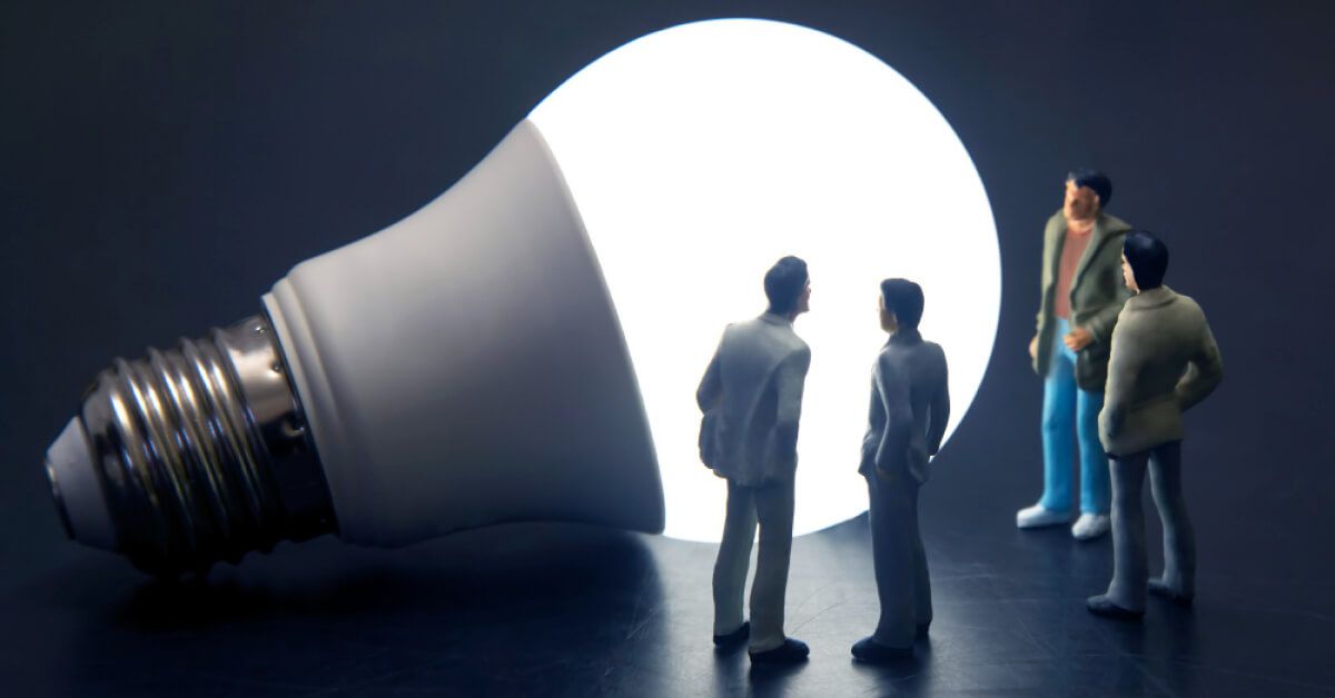 Toy employees surrounding a glowing bulb