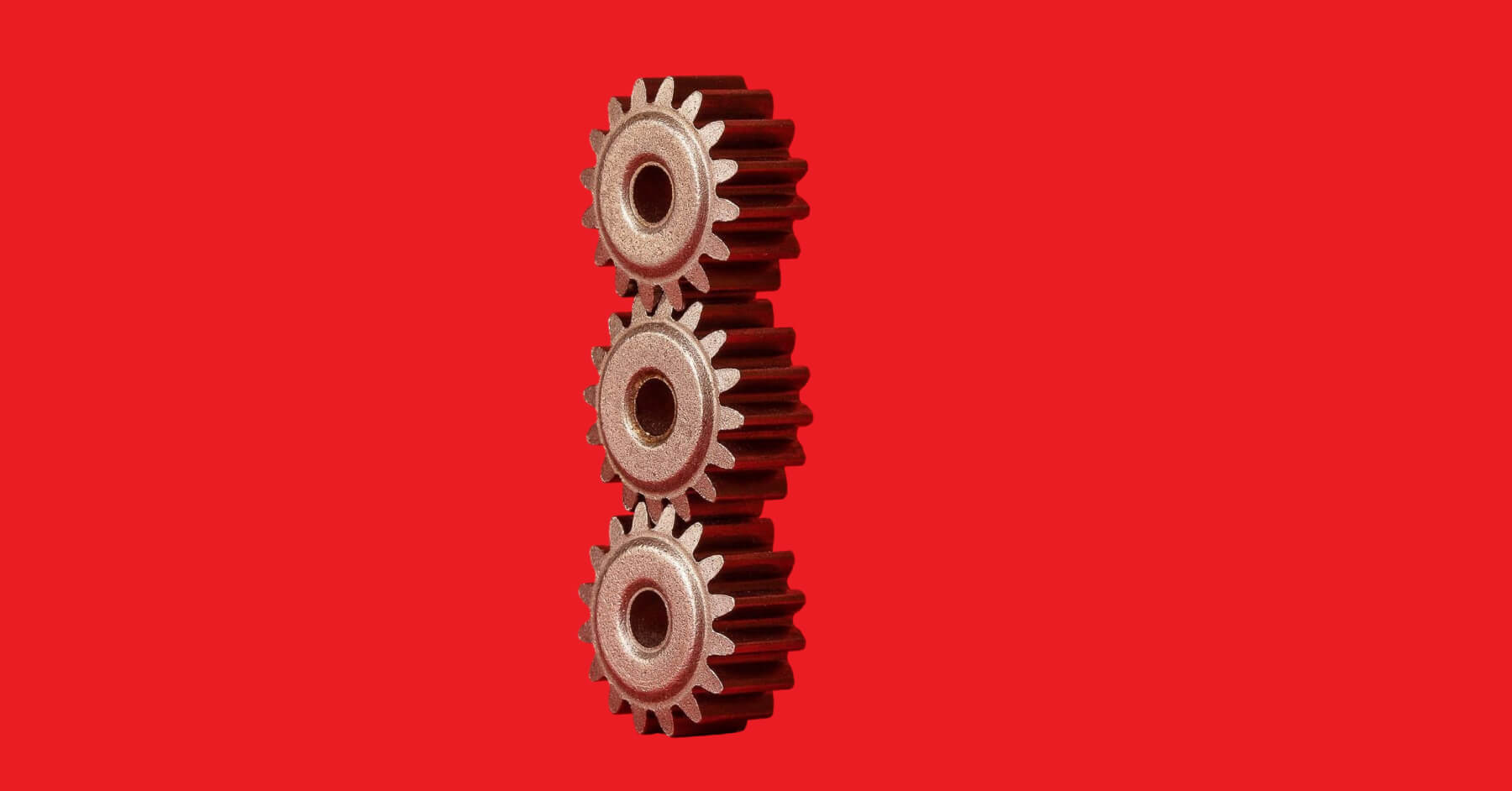 Three gears on top of each other against a red background