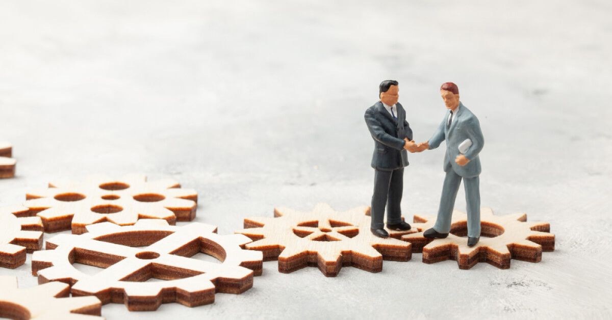 Employee toys shaking hands on top of wooden gears