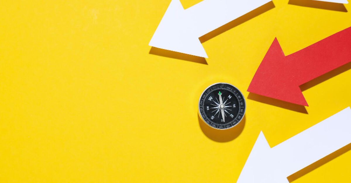 A compass leading a red arrow surrounded by white arrows