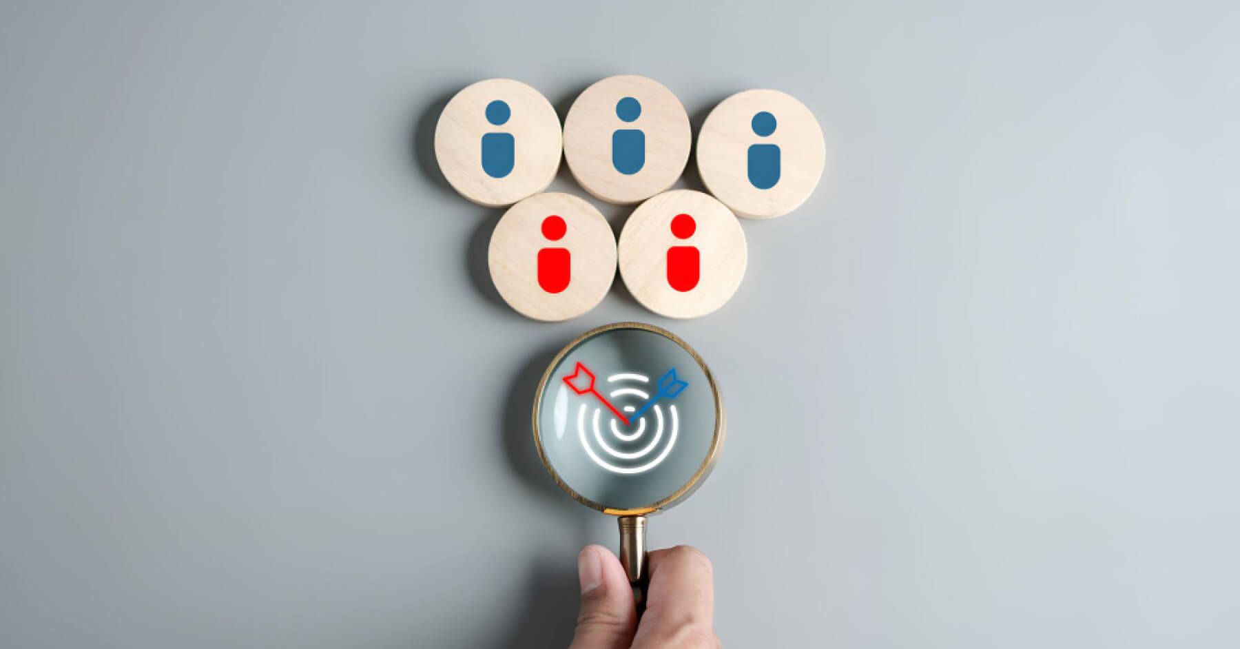 Magnifying glass zooming at a target along with employee wooden blocks