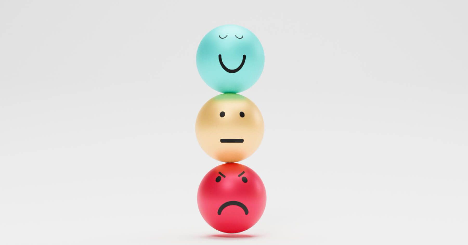 A red angry ball, a golden emotionless ball and a green happy ball placed on top of each other