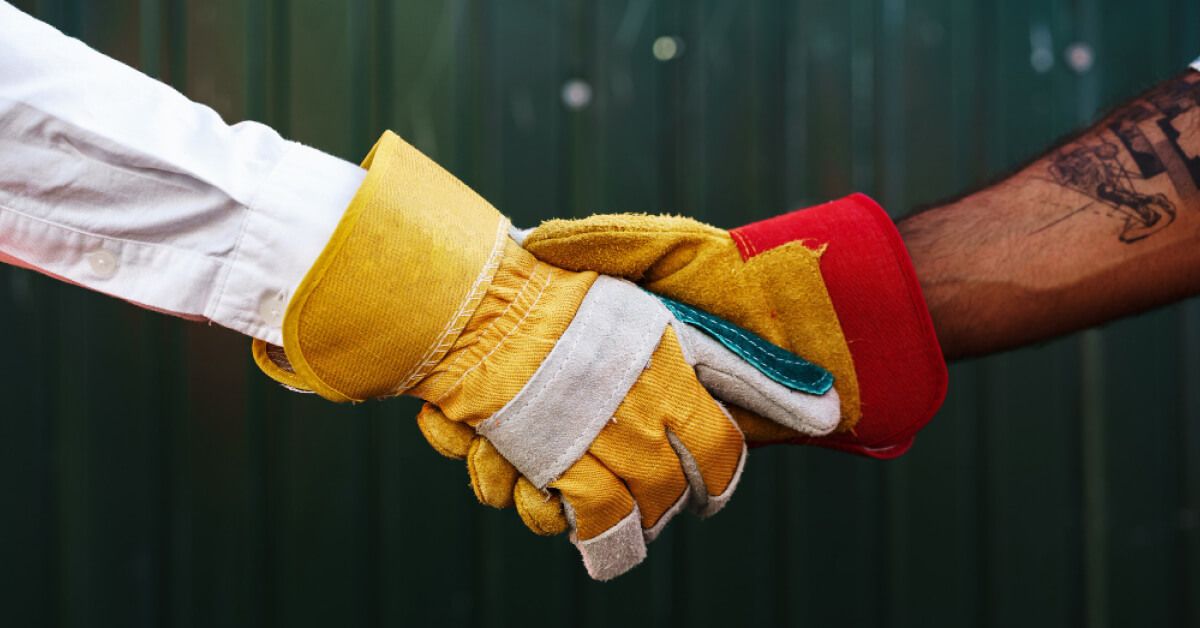 Gloved hands of manufacturing workers shaking each other