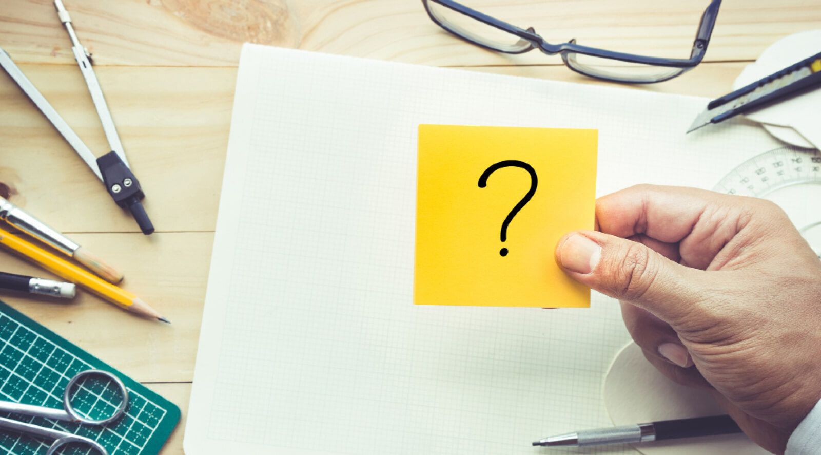 hand holding a sticky note with a question mark