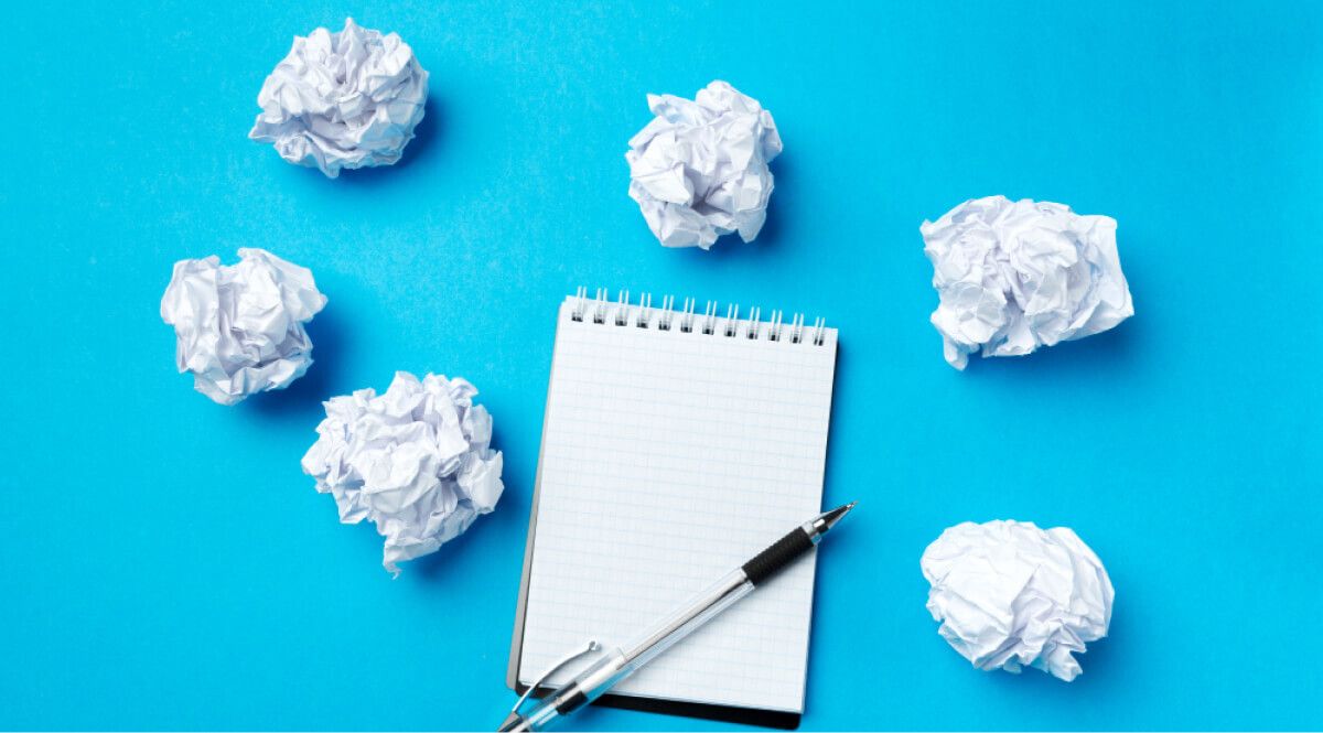 Crumpled paper and pen along with a notebook