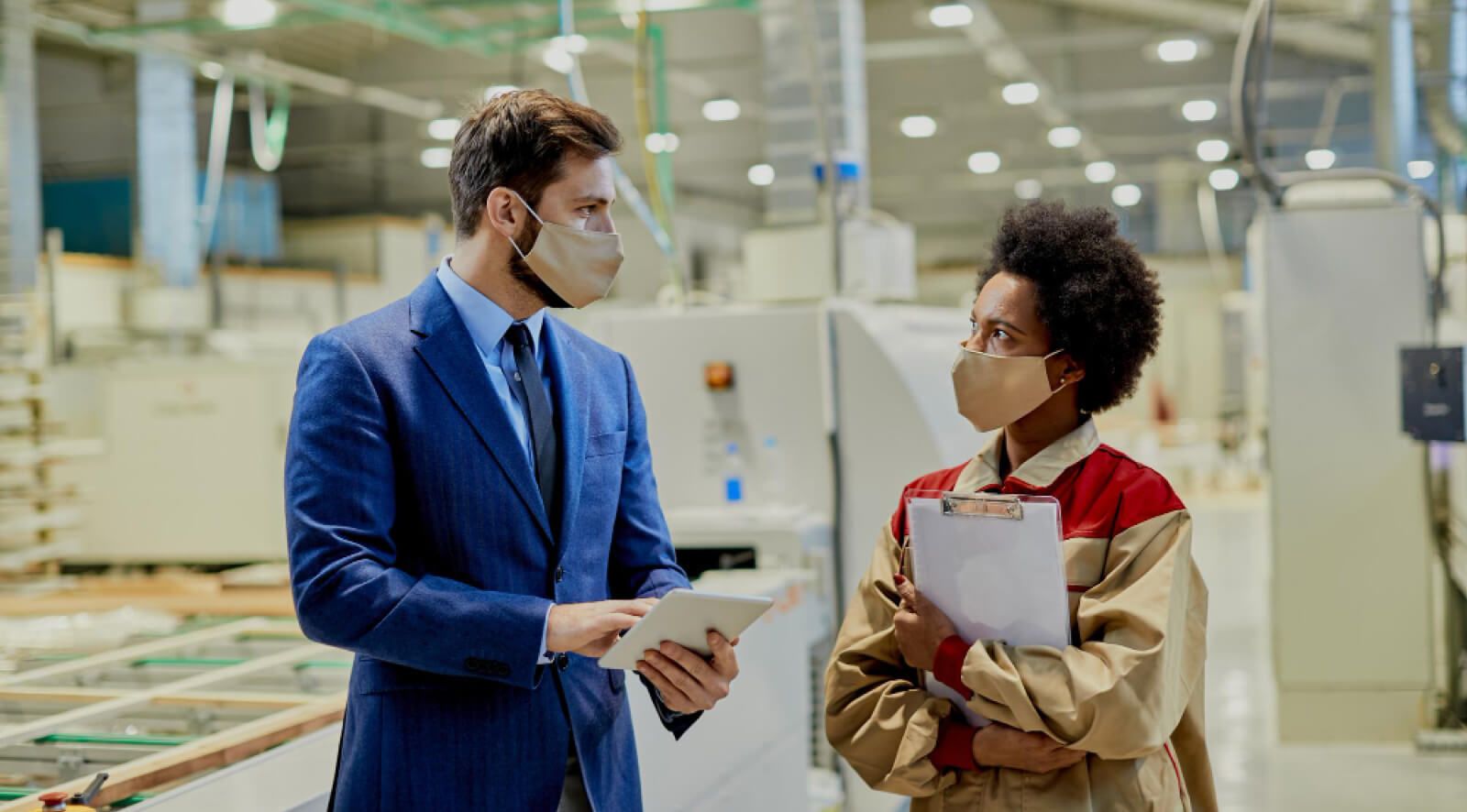 Manufacturing worker listening to a man in suit