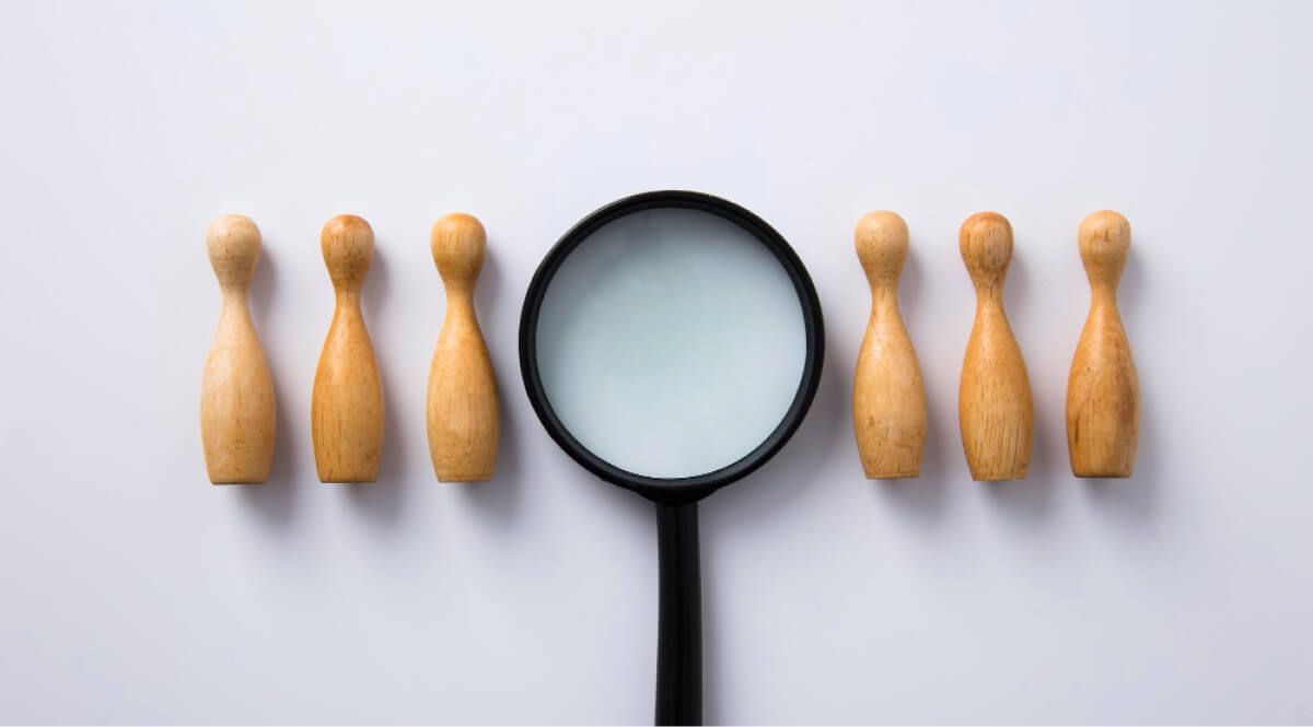 Magnifying glass placed next to rows of wooden people