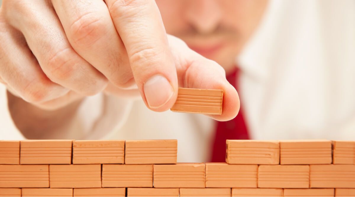 a man putting up a brick model peice in its place