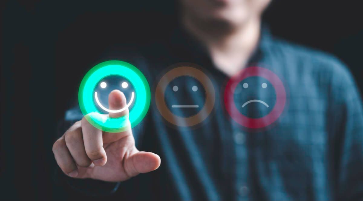 Man touching a happy emoji in screen amongst satisfied and bad emojis