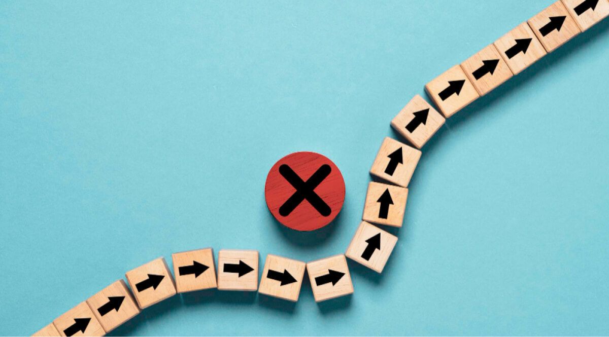 A red wooden circle with an X mark interrupting a row of arrow wooden blocks