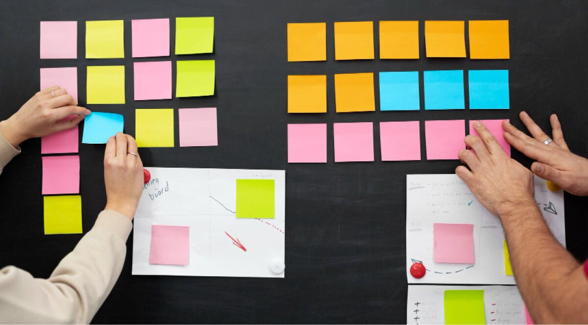 2 people putting up sticky notes