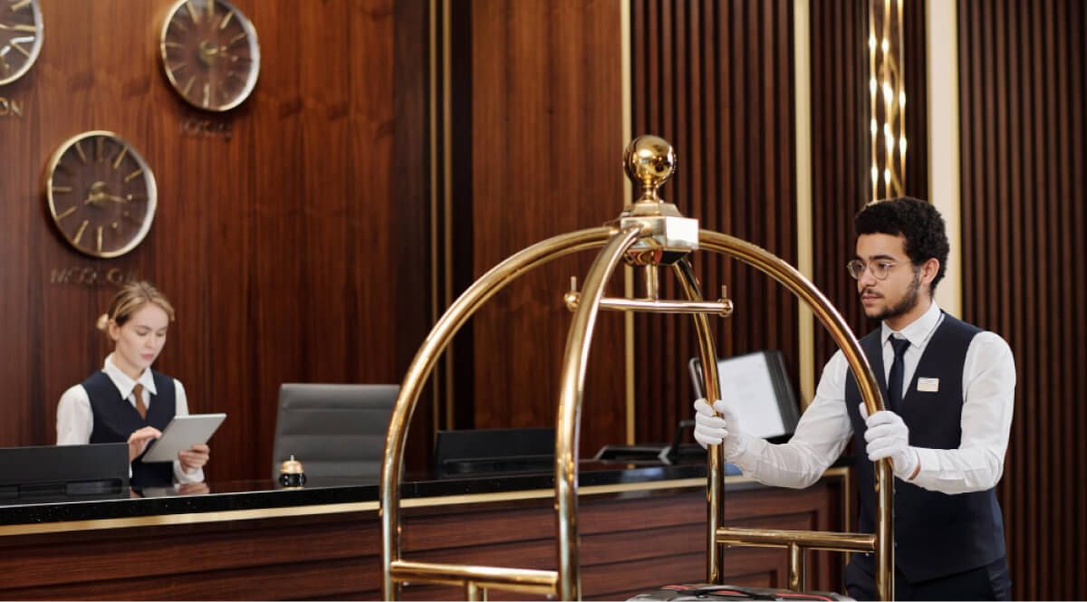 young bellboy uniform pushing cart with suitcases along reception