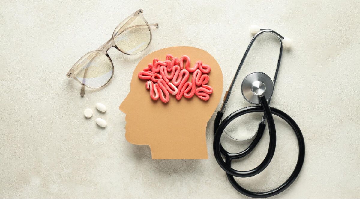 Mockup of a cardboard skull with clay rolled brain next to stethoscope, pills and specs