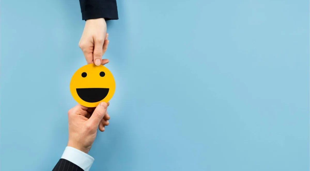 Employee handing a smiley emoji card to an employer